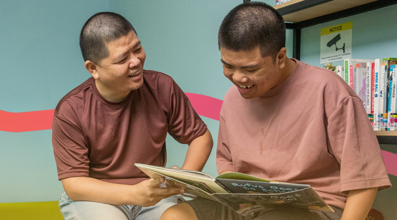 A father and son seated together reading a book