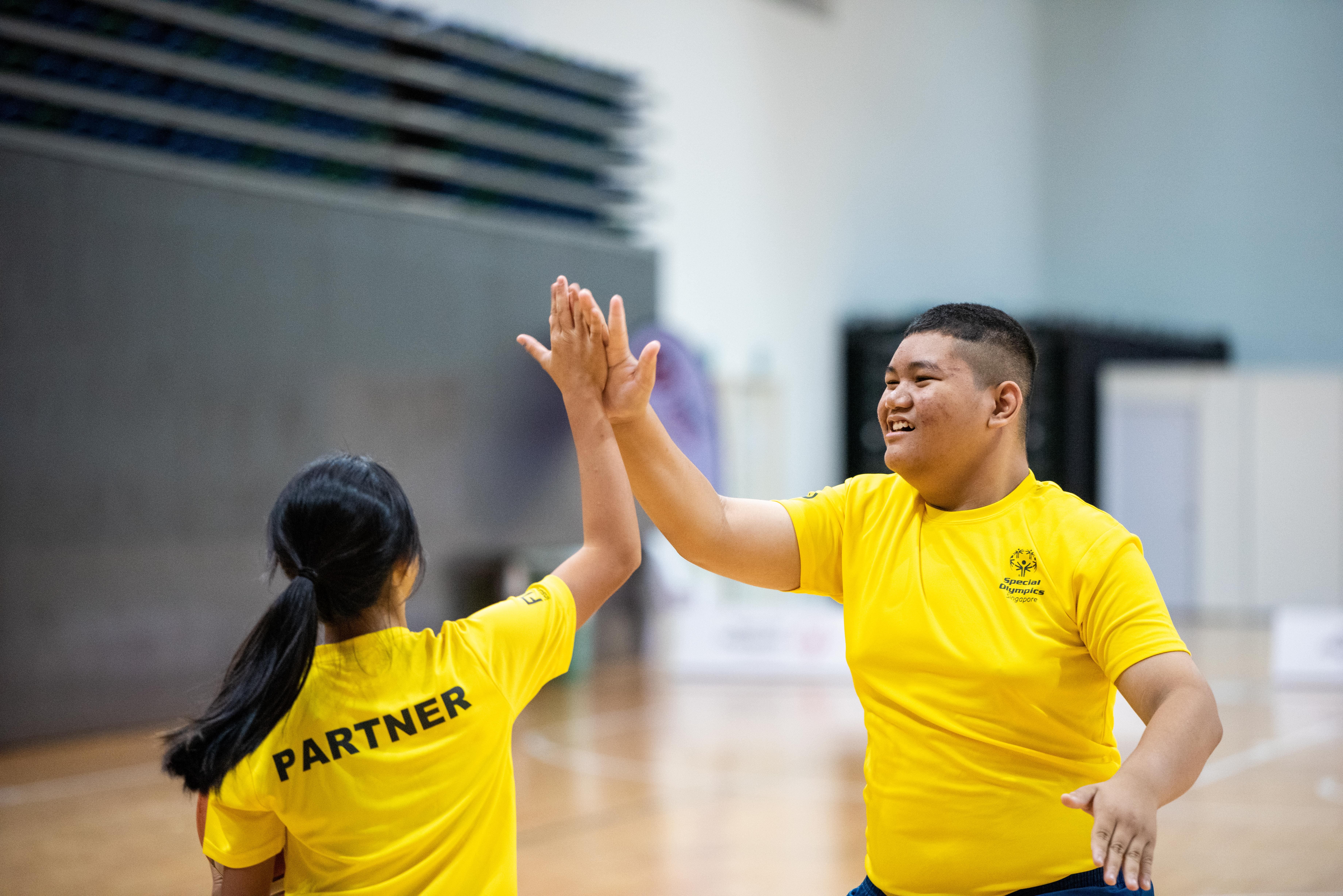 Photo of an Unified partner and an athlete with special needs performing high five during Play Inclusive